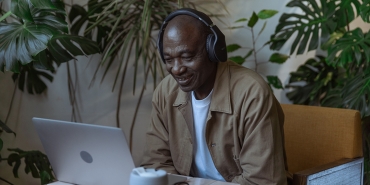 Older man smiles in front of laptop